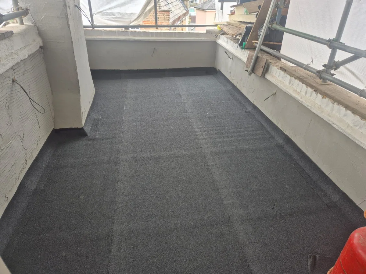 Balcony floor with a dark waterproofing surface beside glazing