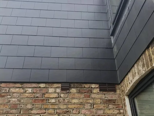 Slate-clad roof edge beside brickwork