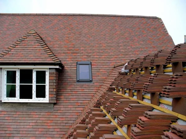 Tiled roof renewal with tiles stacked beside an exposed section